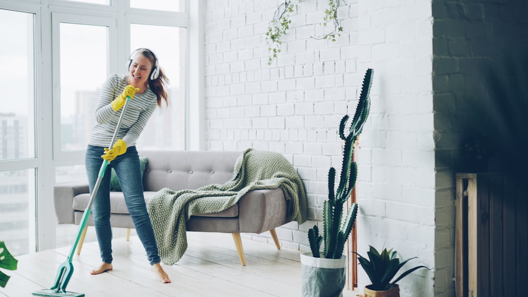 why-choose-us Pretty blond girl is washing floor with flat plastic mop and listening to music in headphones, dancing and singing during routine housework in beautiful apartment.